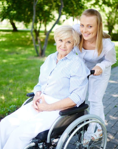 Female caregiver walking with senior patient in park